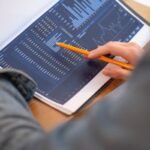 Focused image of hands analyzing business graphs and charts in a folder, highlighting data insights.